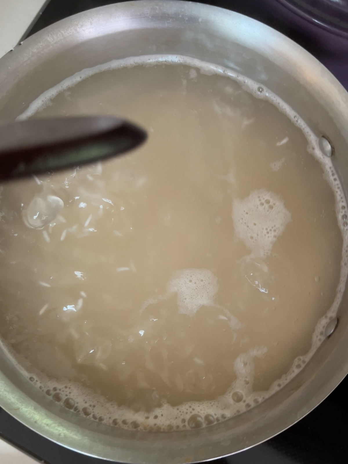 A pot of water with rice coming to a boil.