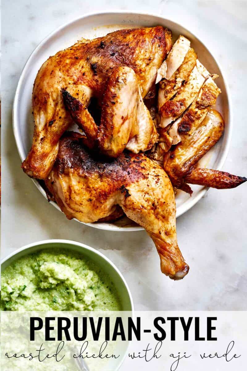 Stack of roasted chicken next to green sauce.