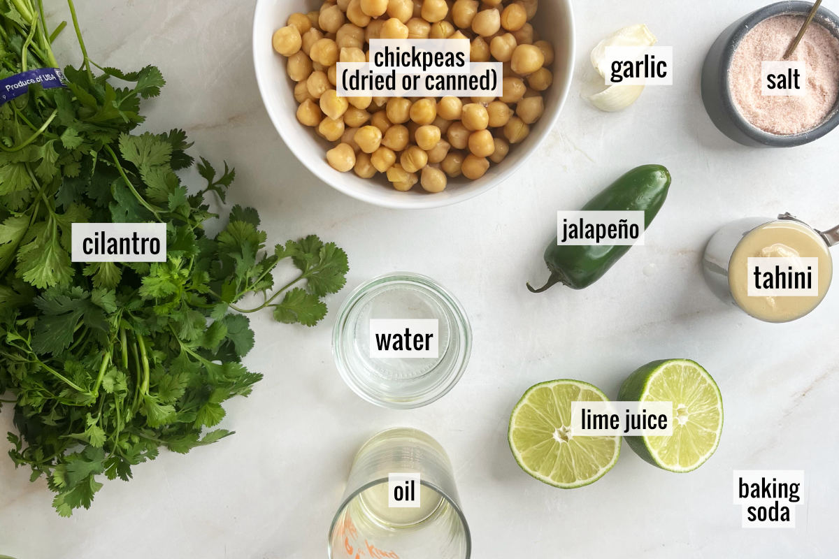 Cilantro, chickpeas, and other hummus ingredients on a white countertop.