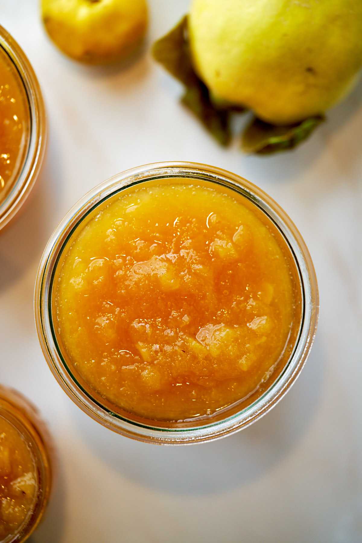 Top view of golden orange jam in a glass jar.