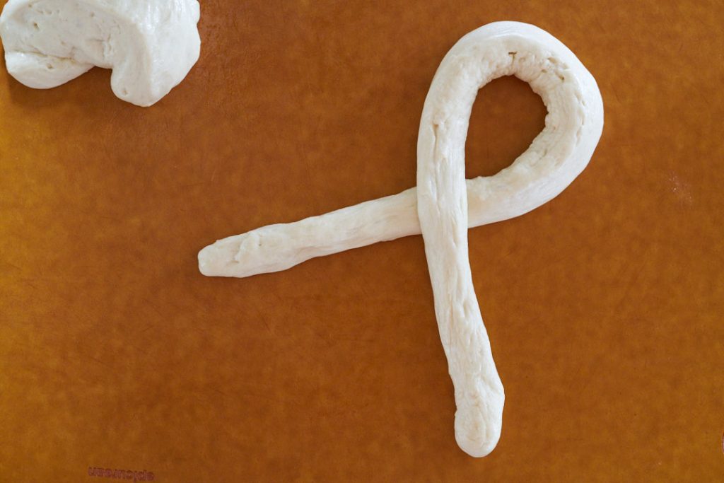 Dough crossed into a loop on a brown cutting board.