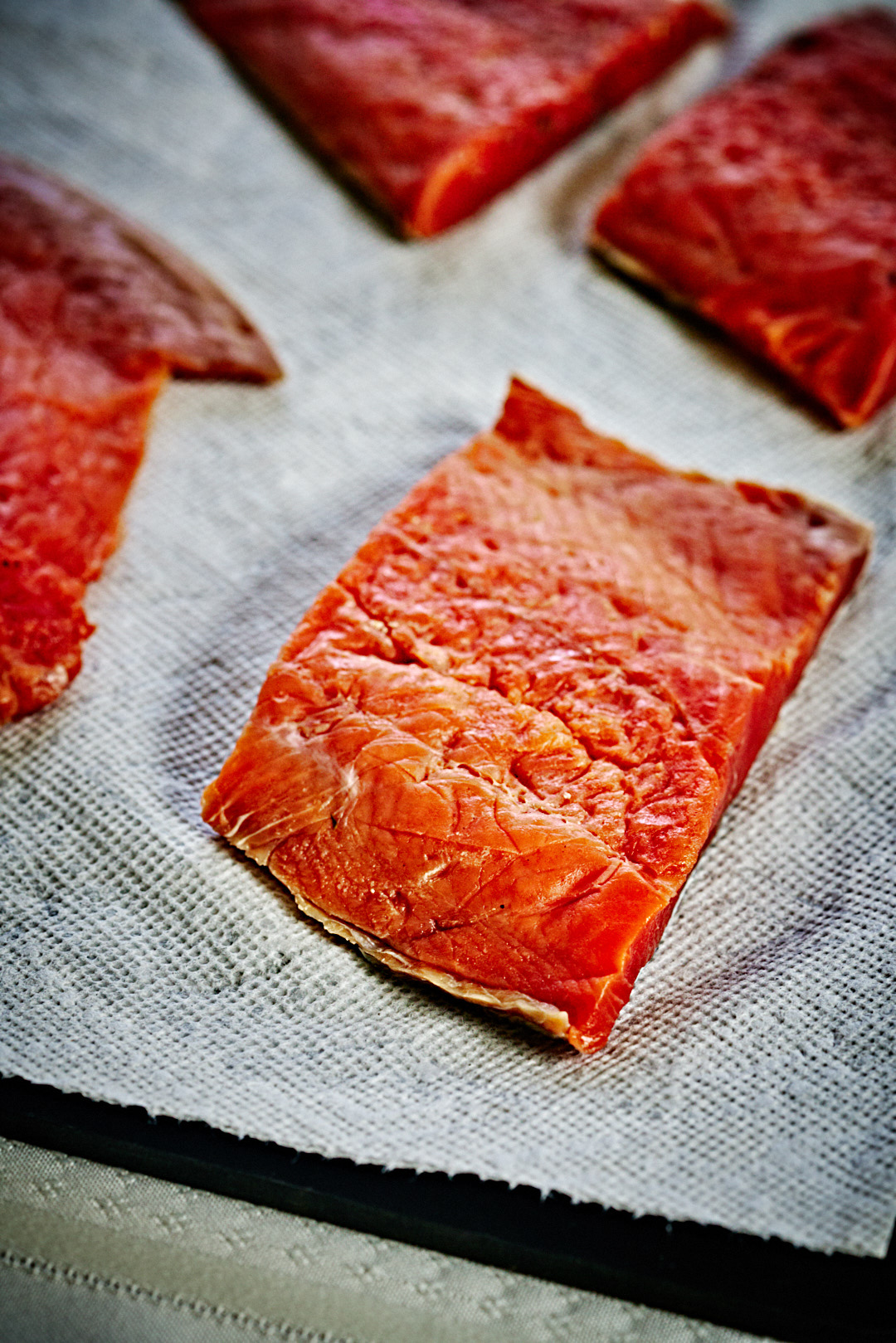 Plain cured salmon fillets resting on a gray tea towel.
