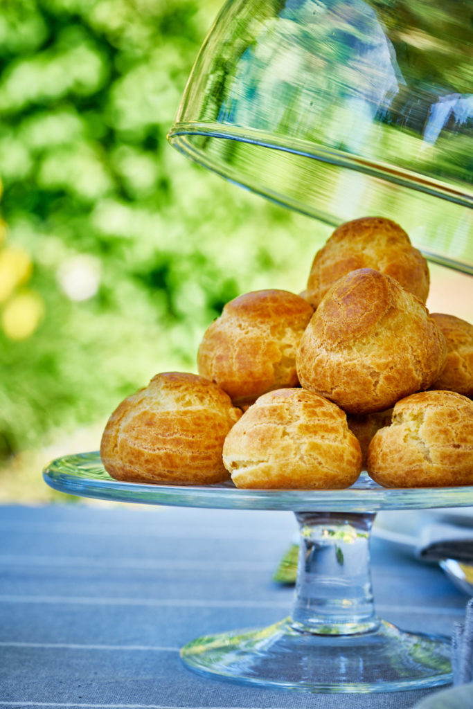 Pastries on a glass pedistol with a cloche in the air.