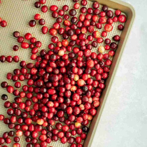 Cranberries on a gold baking sheet.