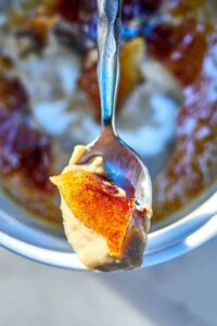 Top view of creme brulee on a spoon resting on a ramekin.