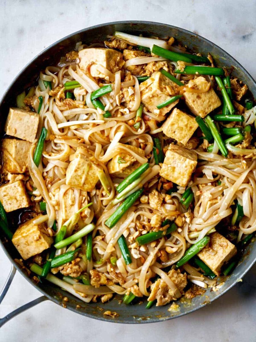 Noodles and tofu in a fry pan.