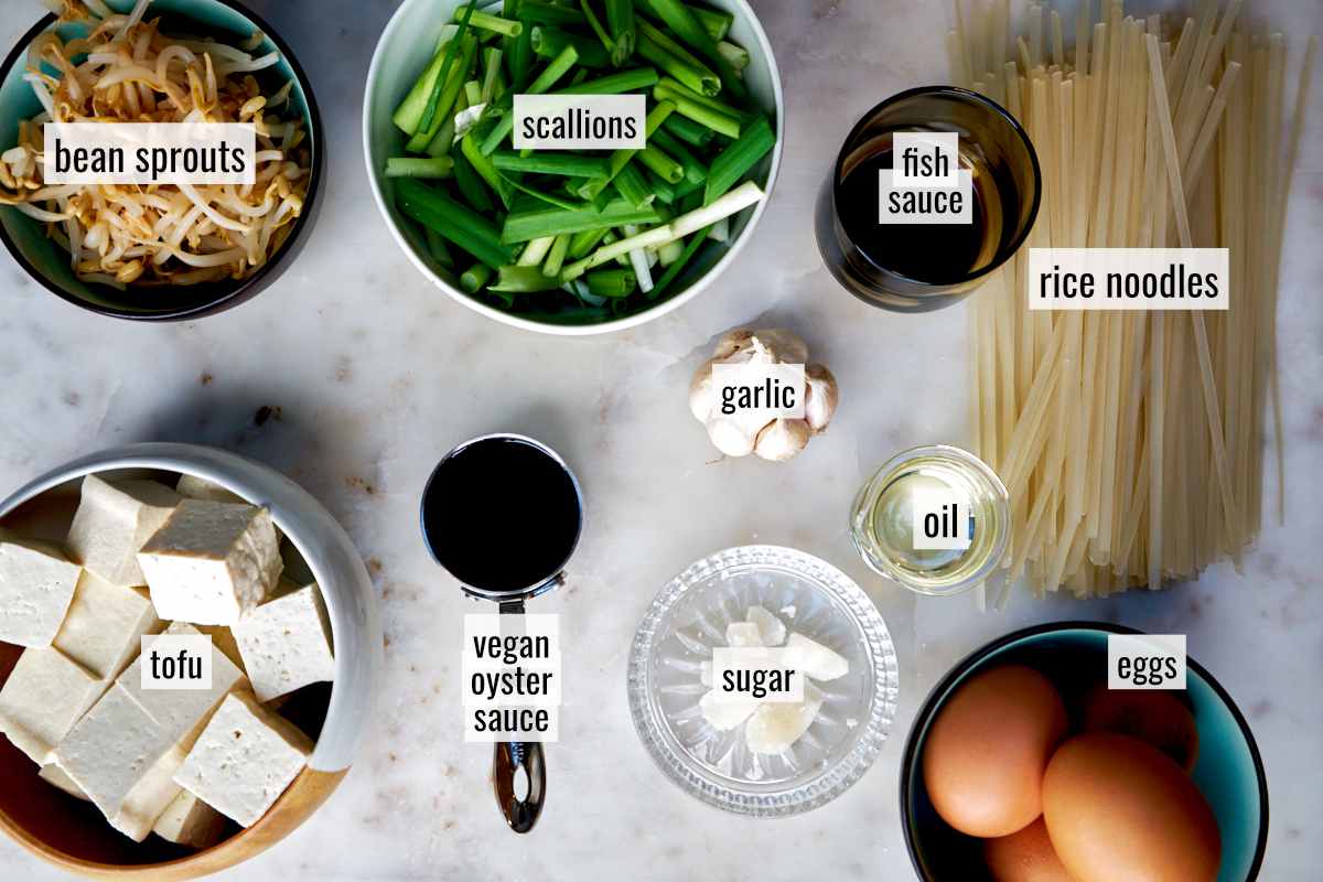 Ingredients for noodle stir fry on a countertop with text labels.