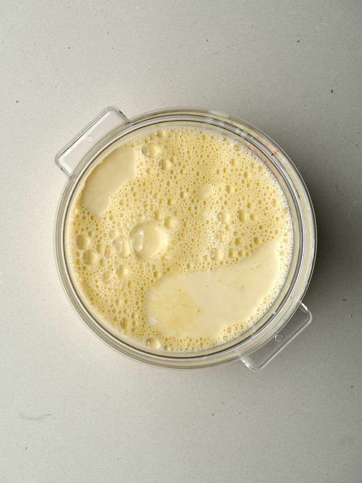 Pale yellow ice cream base in a round, clear container.