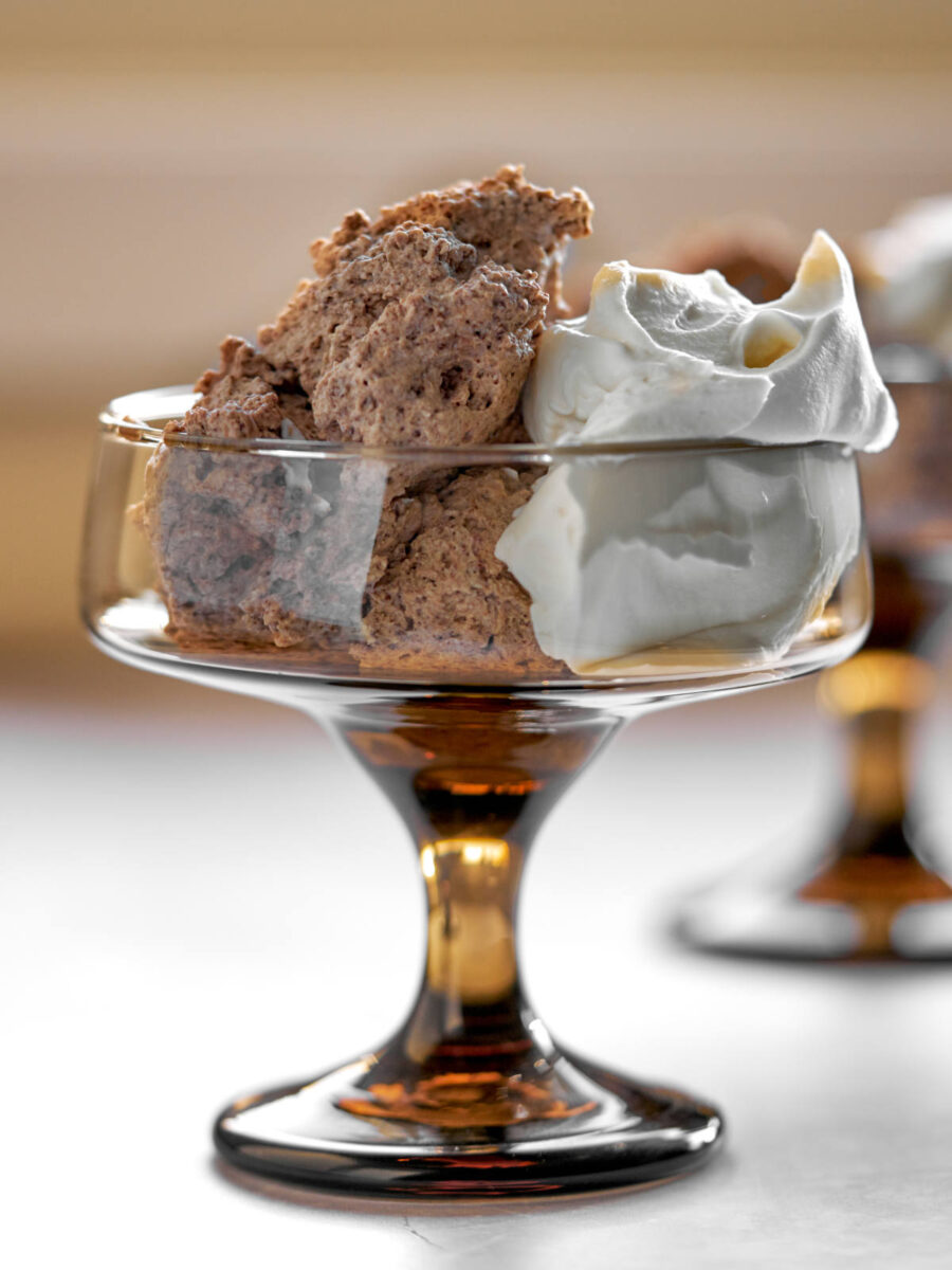 Mousse and whipped cream in a brown pedestal glass.