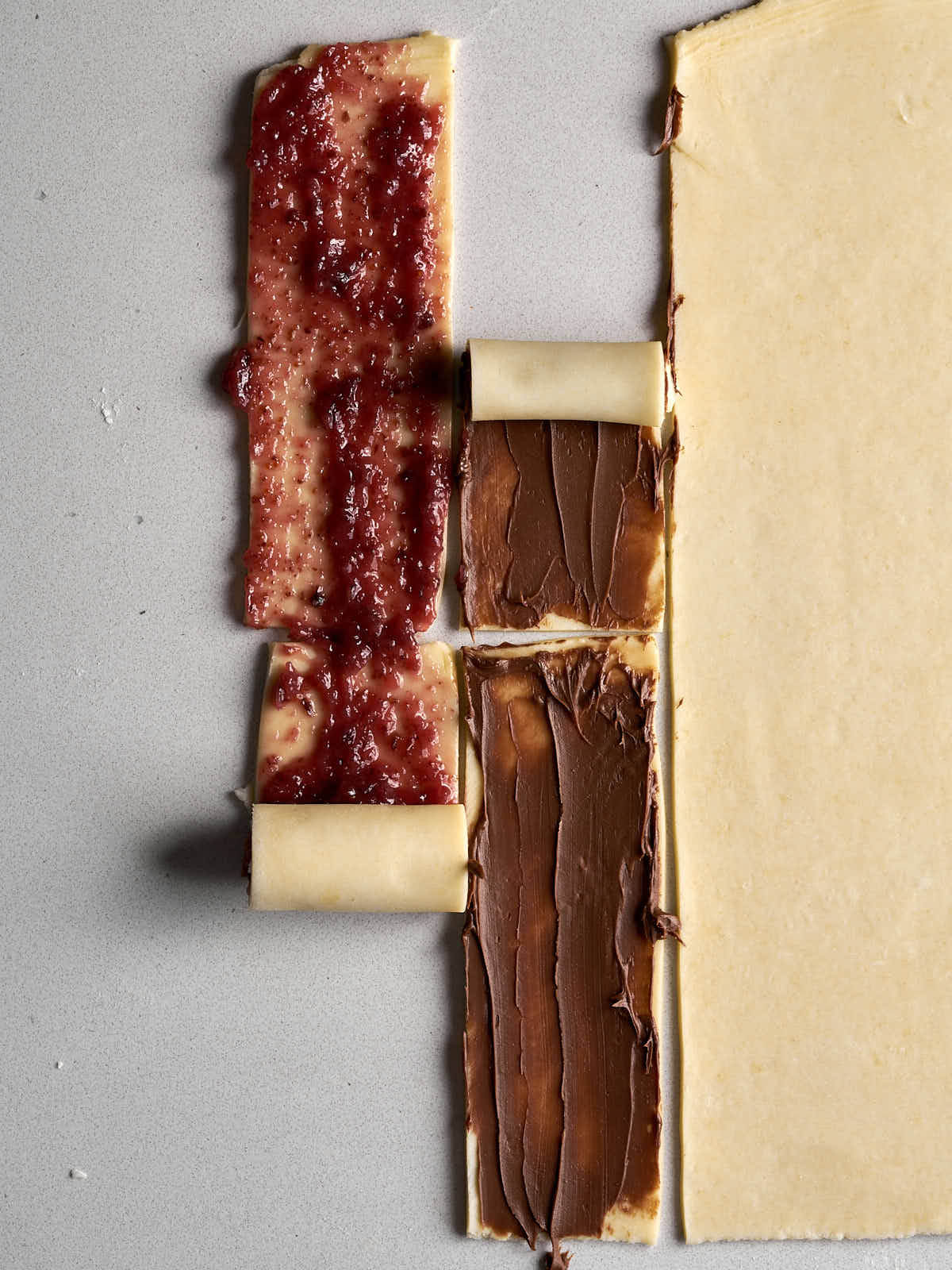 Knife cutting pastry covered in red jam.