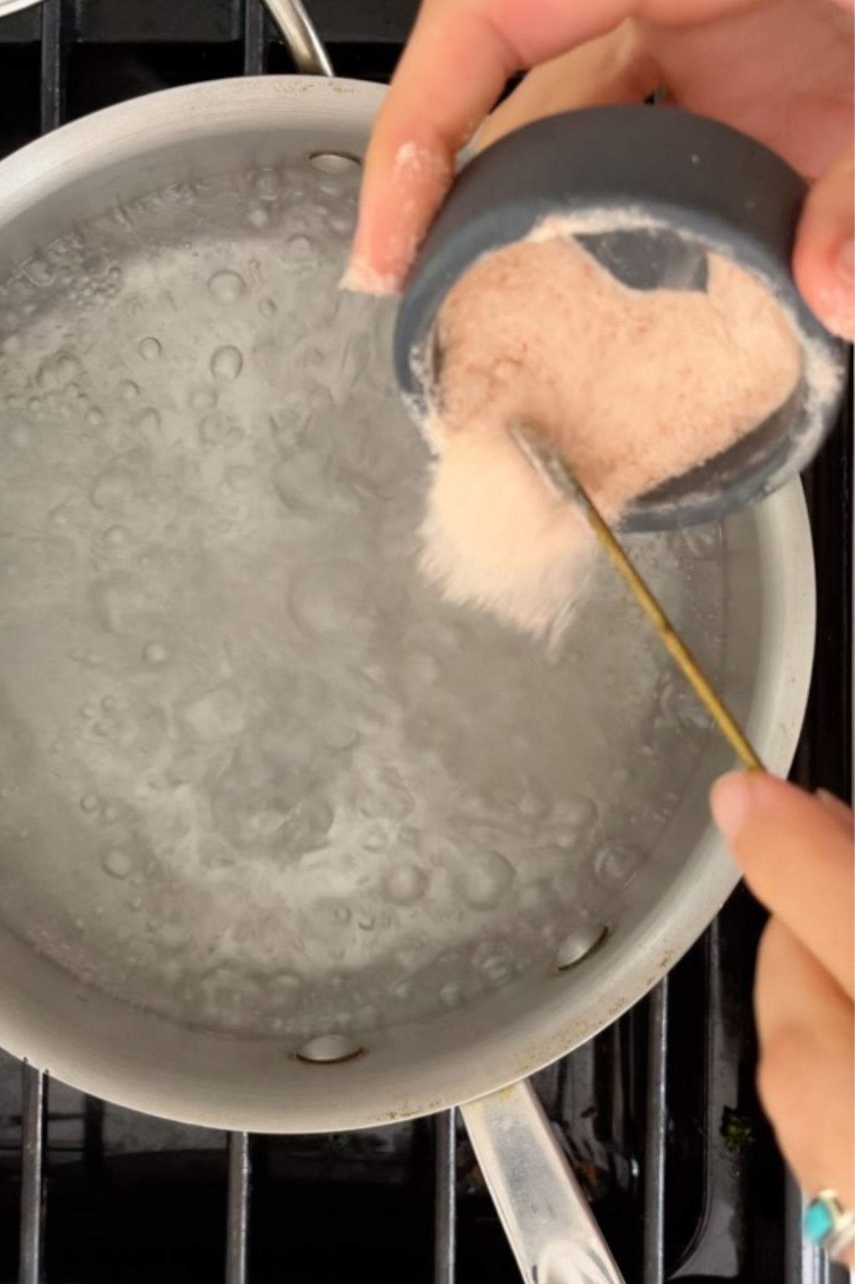Adding salt to a pot of boiling water.