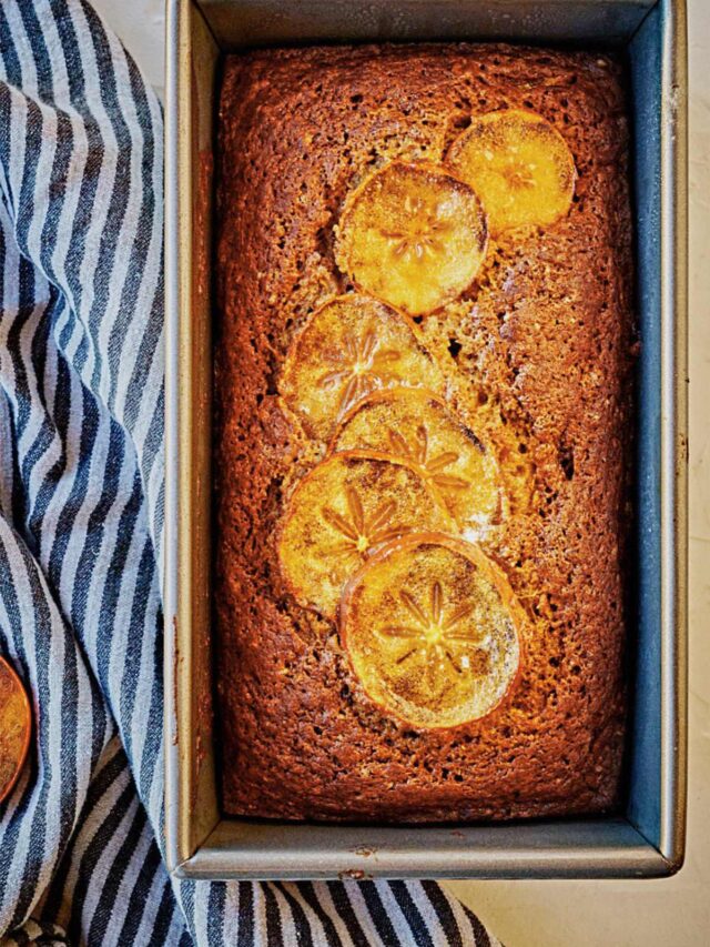 A close up on persimmon bread in a metal loaf tin.