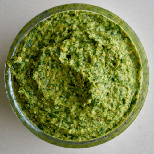 Vibrant green pesto in a glass ramekin.