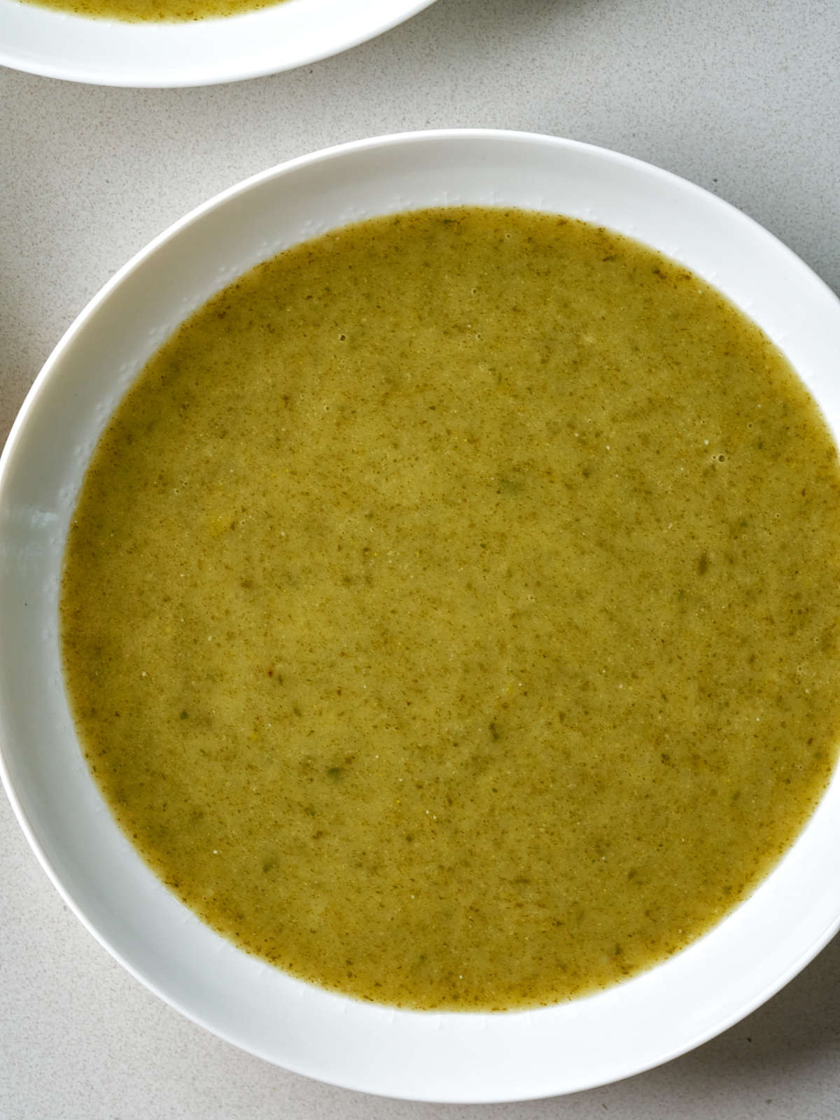 Green puree soup in a white soup bowl.