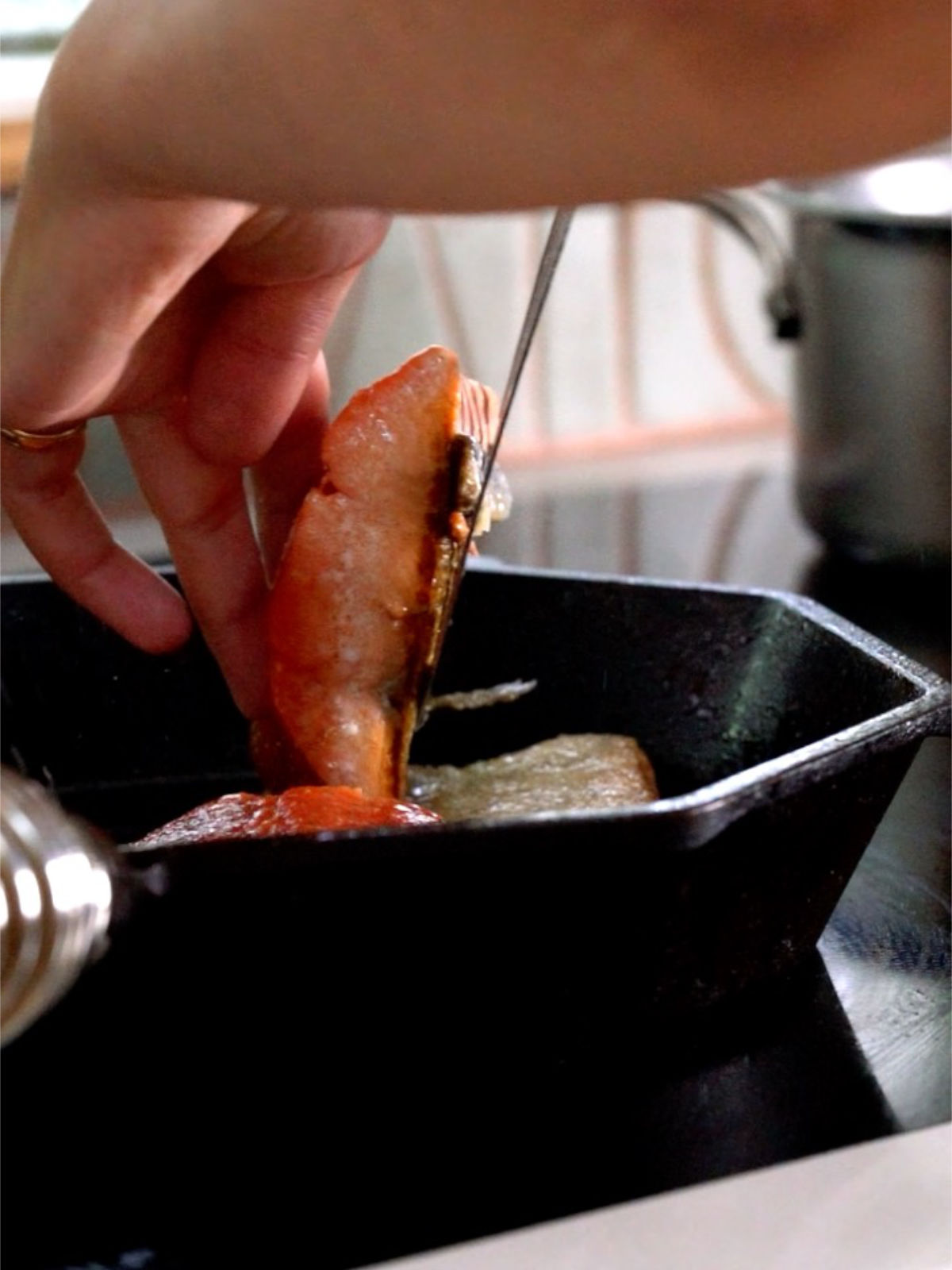 Flipping a salmon filet in a hexagonal cast iron pan.