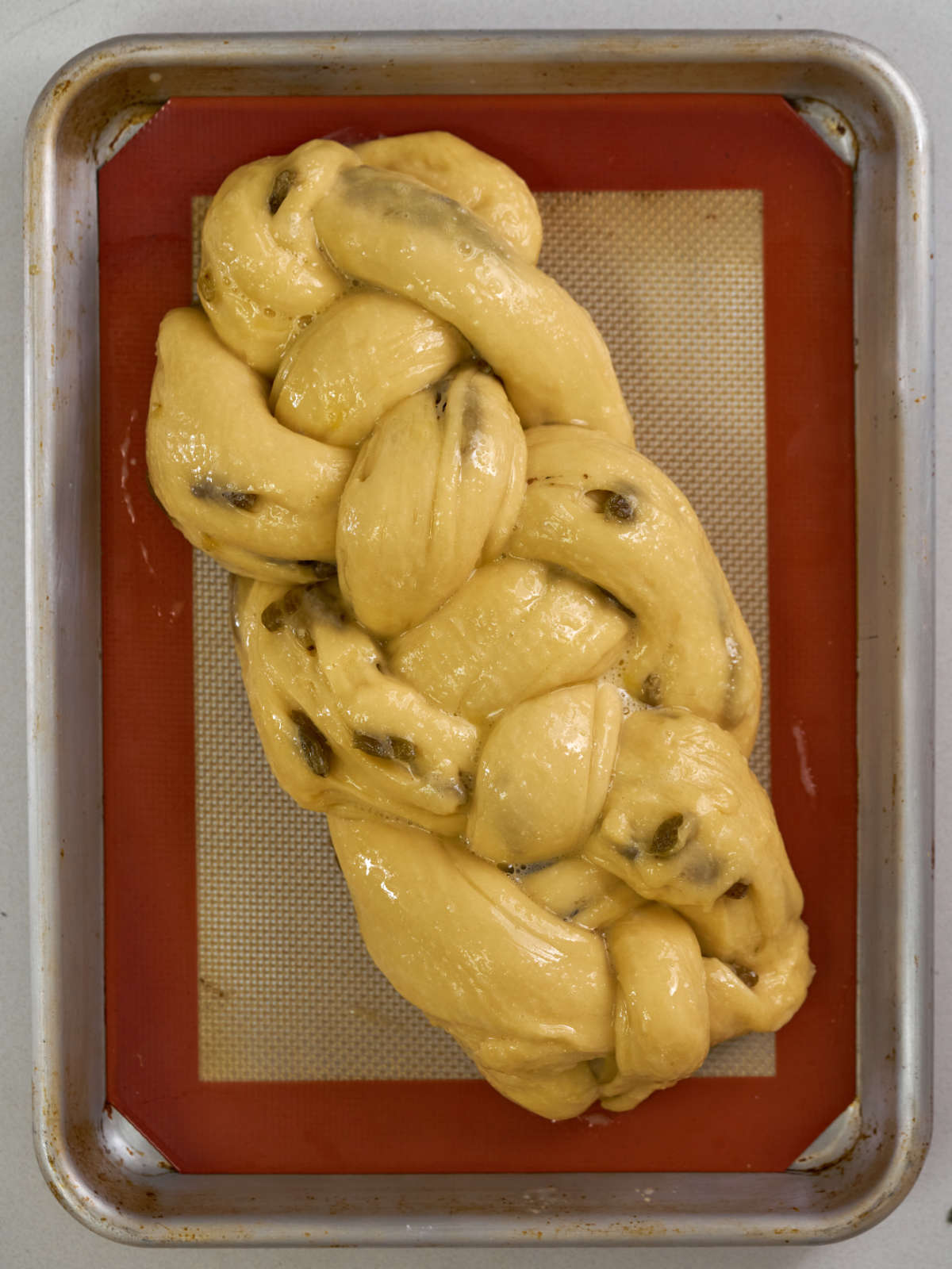 Challah loaf brused with egg wash and studded with raisins.