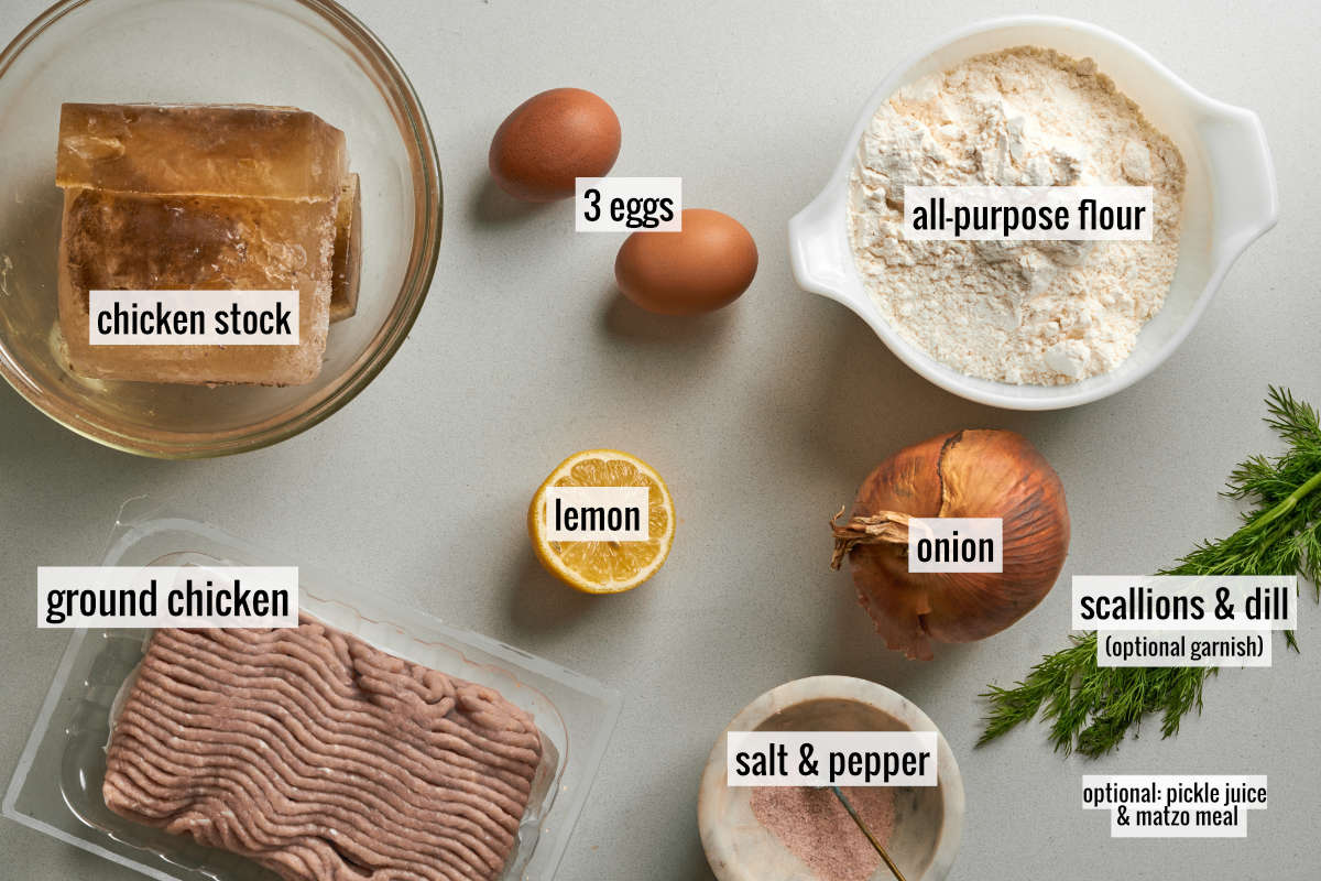 Ingredients like chicken stock, ground chicken, flour, eggs, lemon, and onion on a countertop.