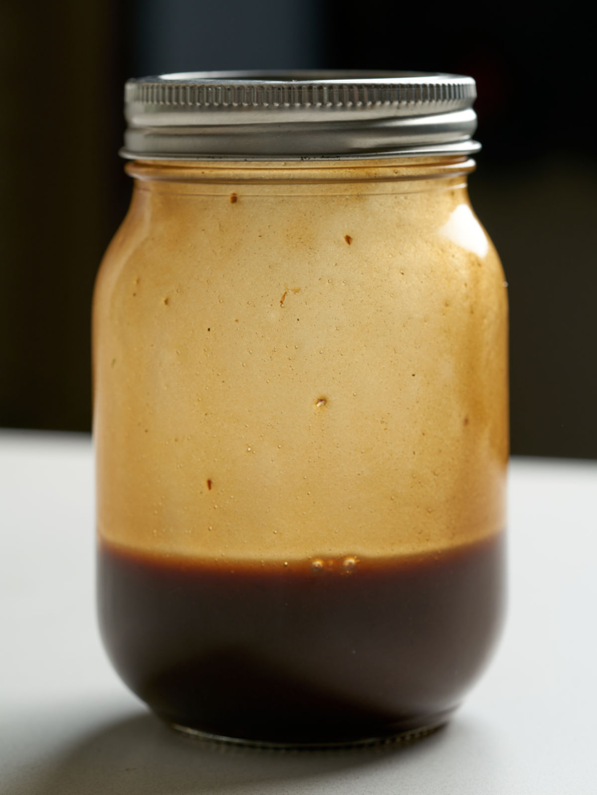 Brown salad dressing in a sealed mason jar.