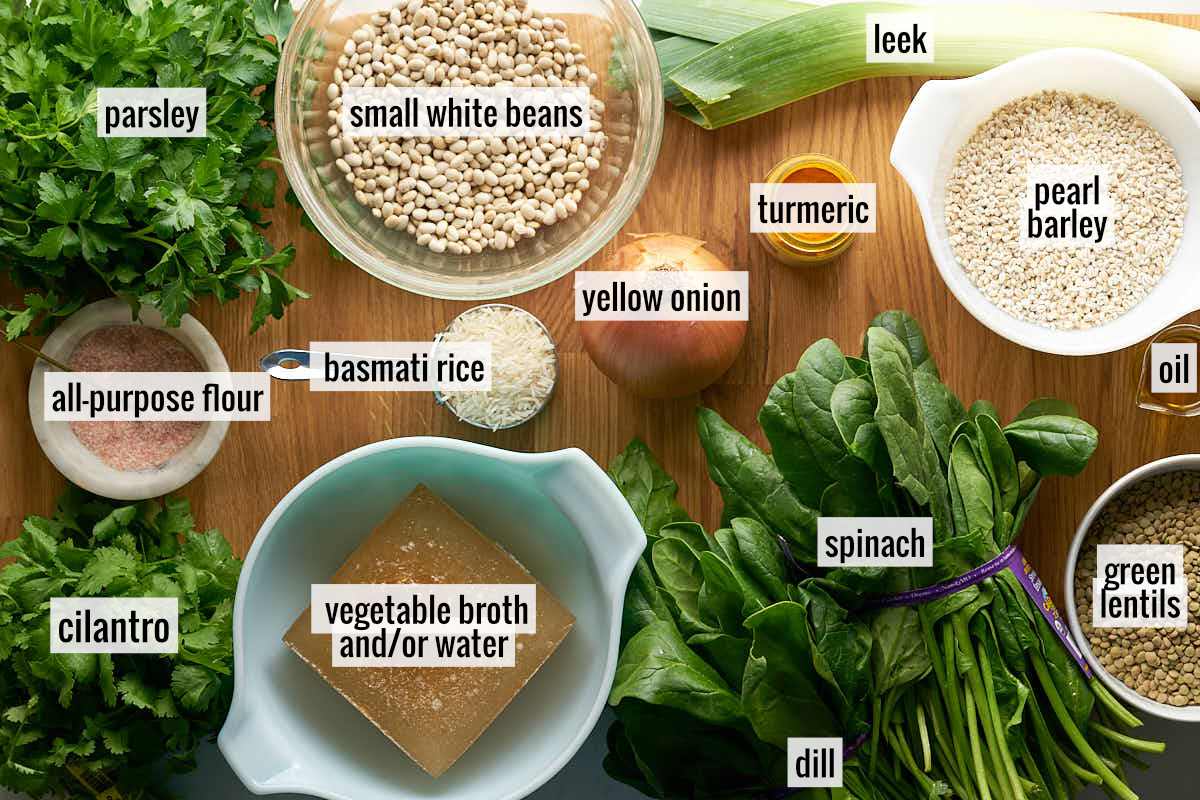 Labeled ingredients to make barley and bean soup on a wood cutting board.