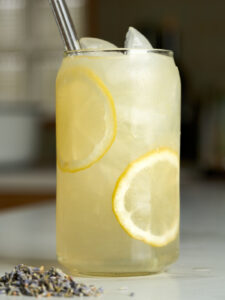 Lemonade in a soda can glass with lemon slices next to lavender buds.