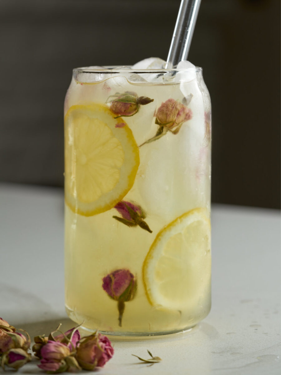 Lemonade in a soda can glass with lemon slices and dried rose buds.