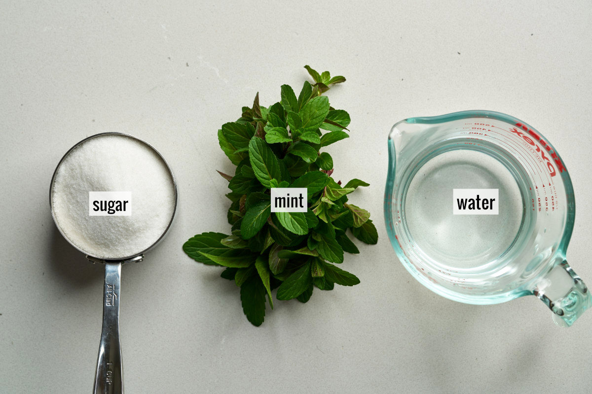 Mint, water, and sugar sitting on a countertop.
