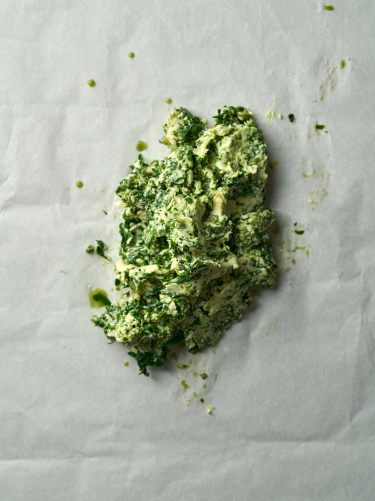 A mound of green and beige butter on top of parchment paper