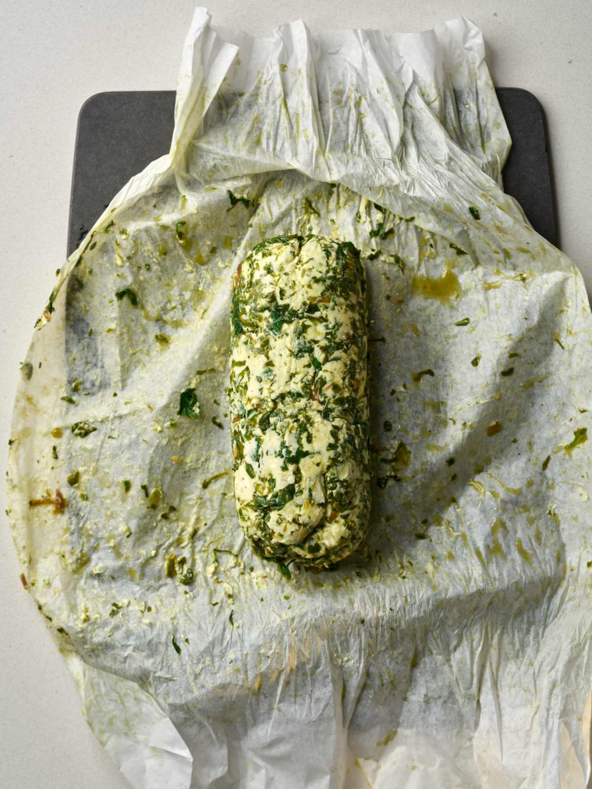 A log of green and beige butter on top of parchment paper