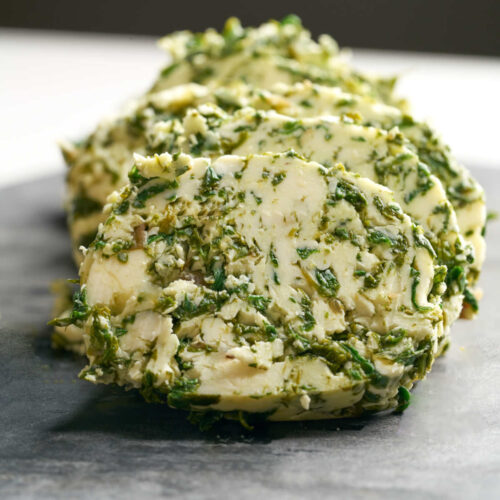 Large circles of green and beige butter on a cutting board.