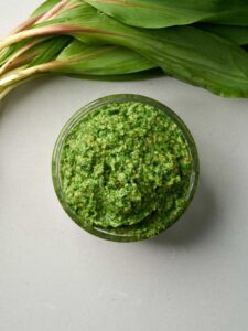 Top down view of a jar of vibrant green pesto.