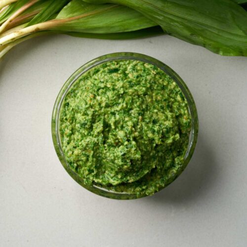 Top down view of a jar of vibrant green pesto.