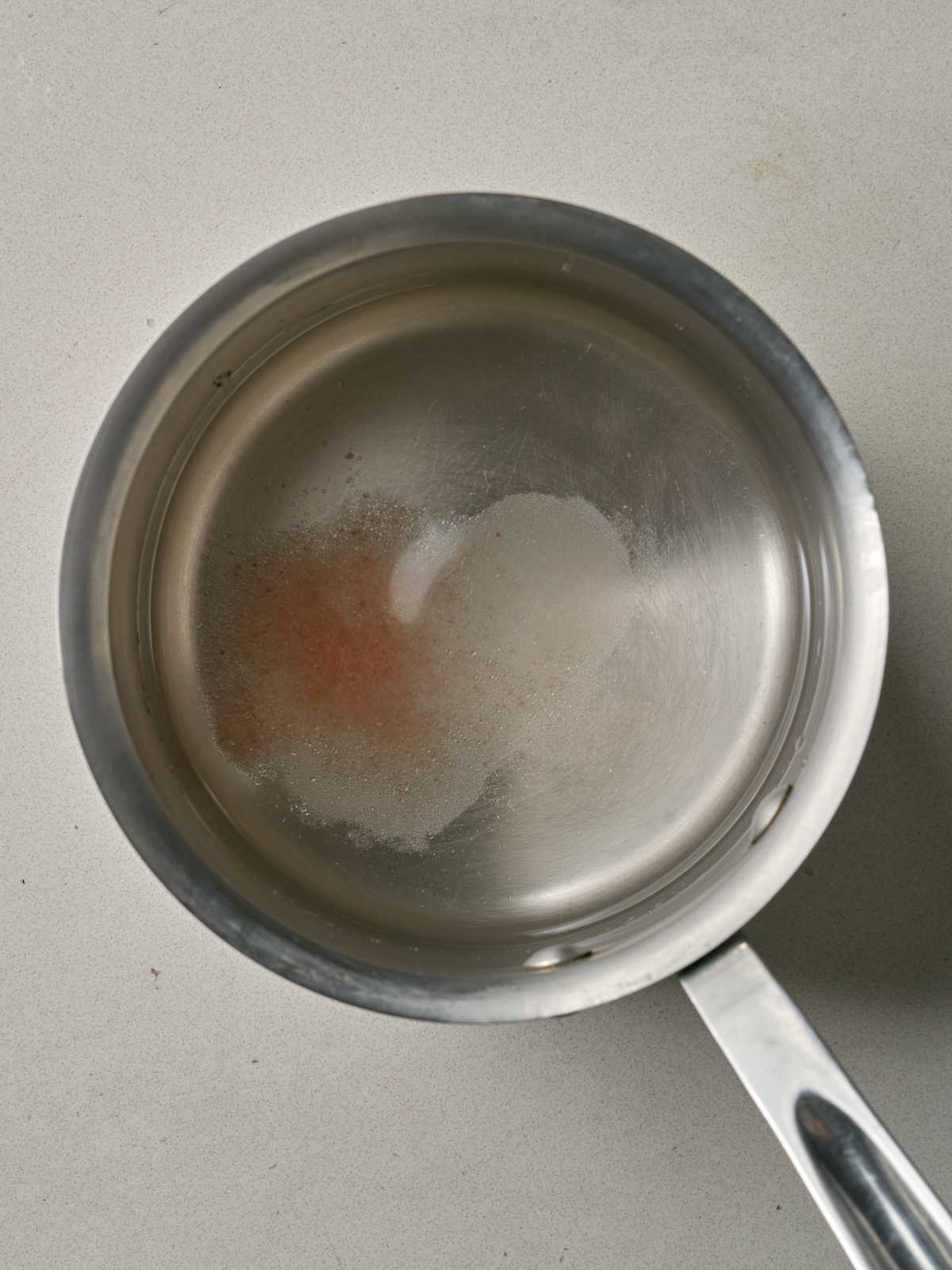 Silver sauce pan with clear water, salt, and sugar