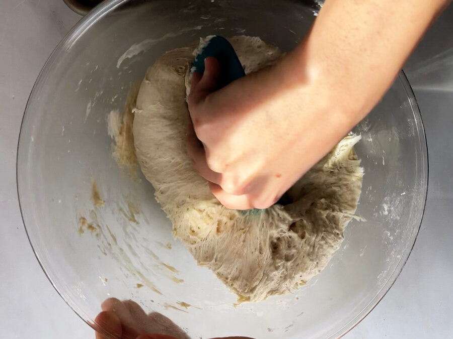 Folding dough in a glass bowl.
