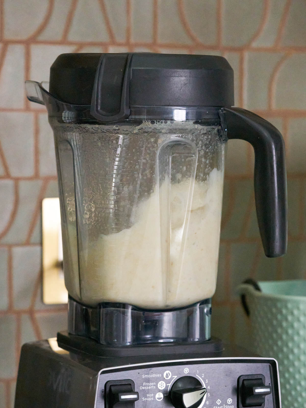 Blender with pale yellow liquid next to a mint colord stand mixer.