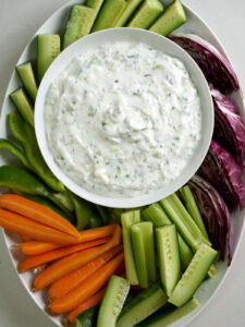 Yogurt dip on a platter of raw veggies.