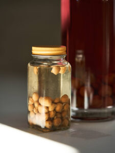 Cherry pits in a small spice jar with yellow tinted vodka.