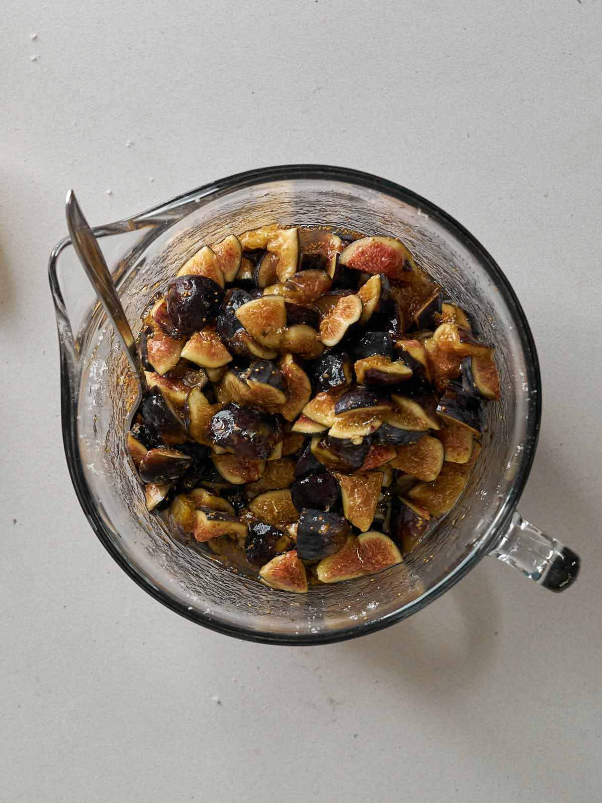 Large glass mixing bowl with a handle filled with macerated figs.