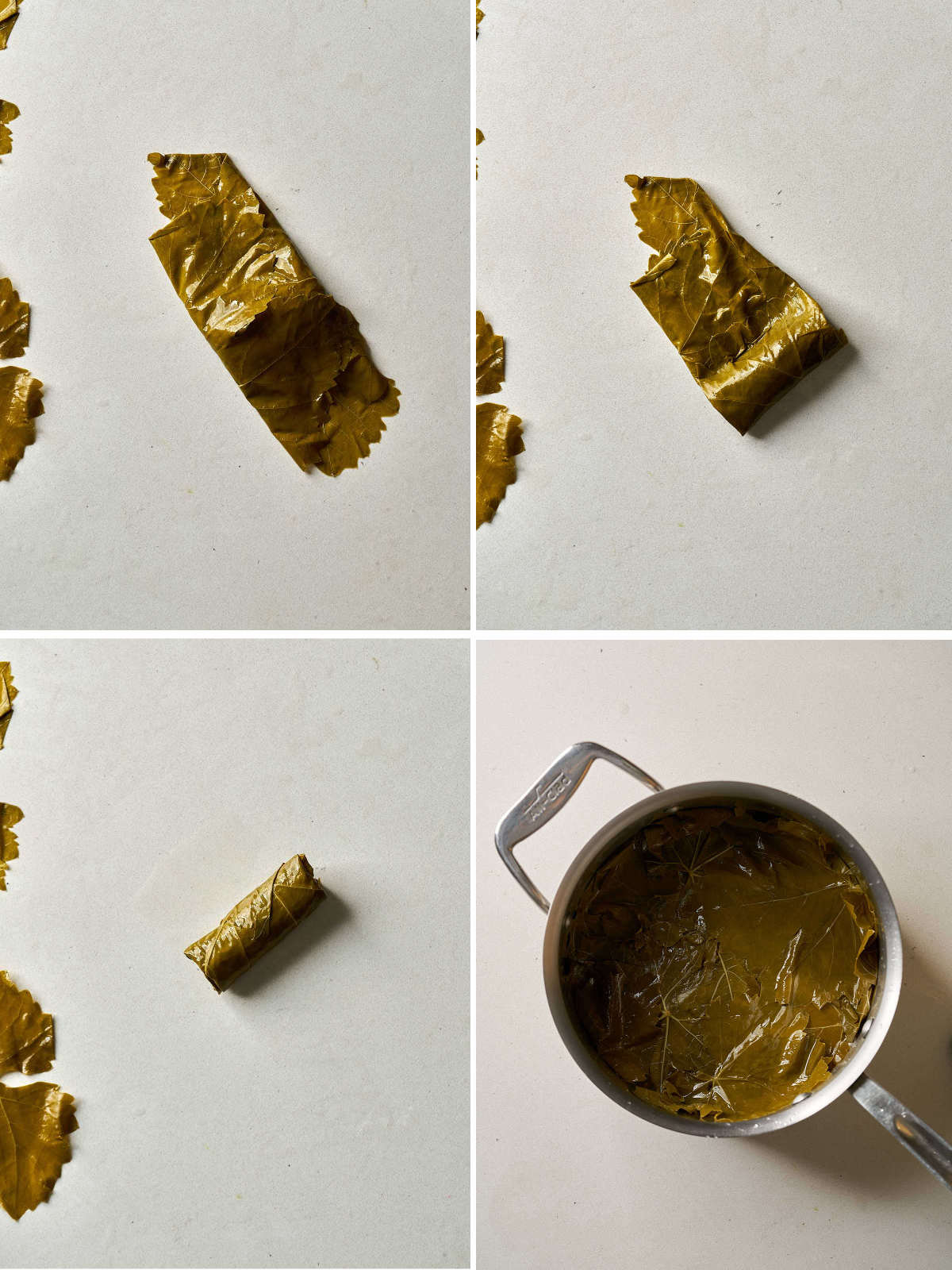 A grape leaf rolled into a small parcel on a countertop next to a pot lined with grape leaves.