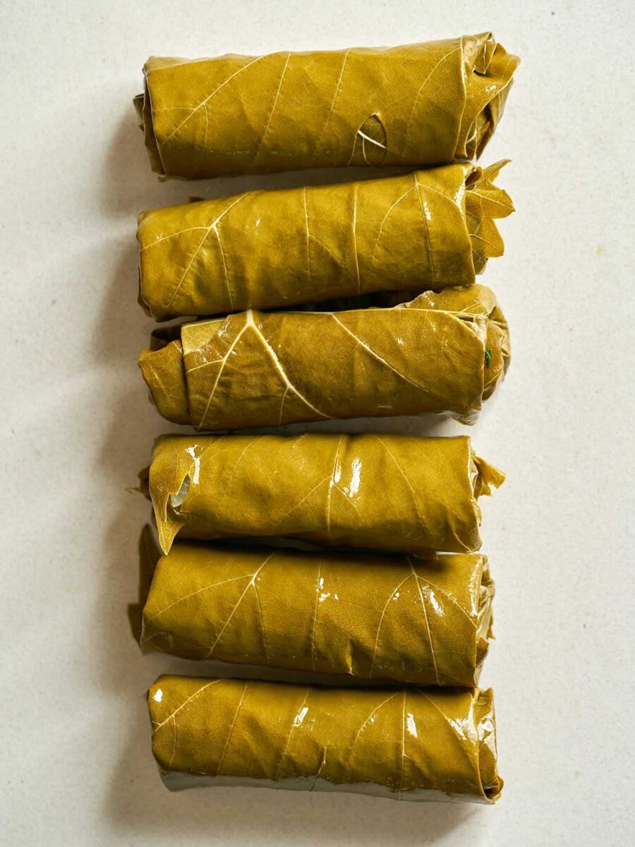 Six rolled cylinders of stuffed grape leaf parcels.