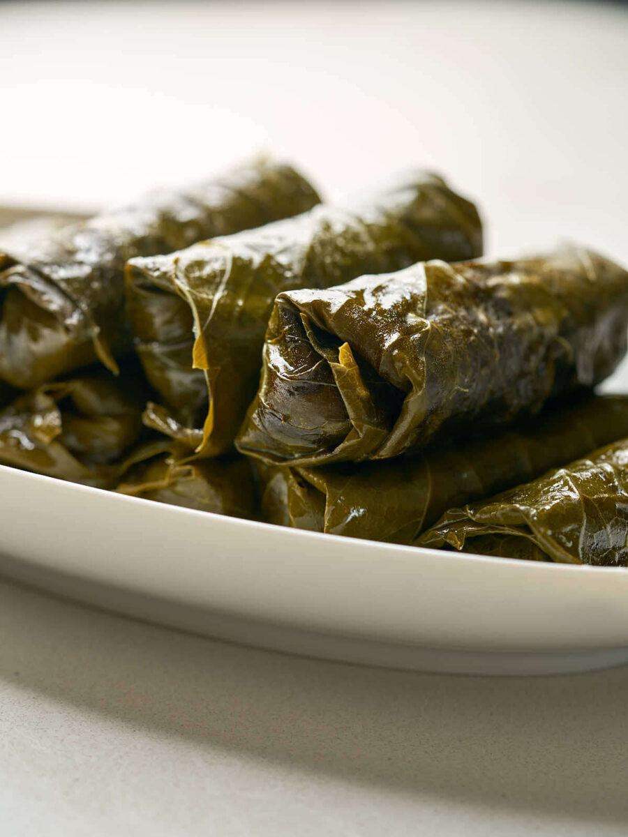 Side view of rolled grape leaf parcels on a white plate.