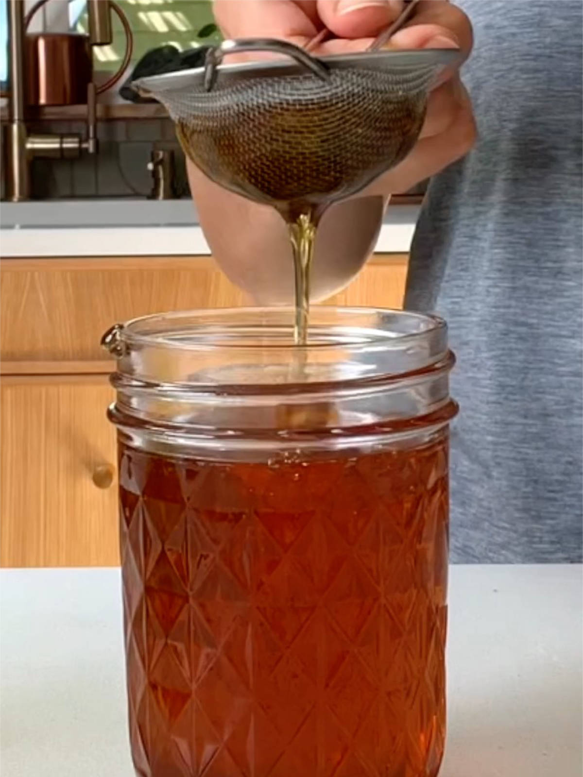 Small strainer over a jar of honey.