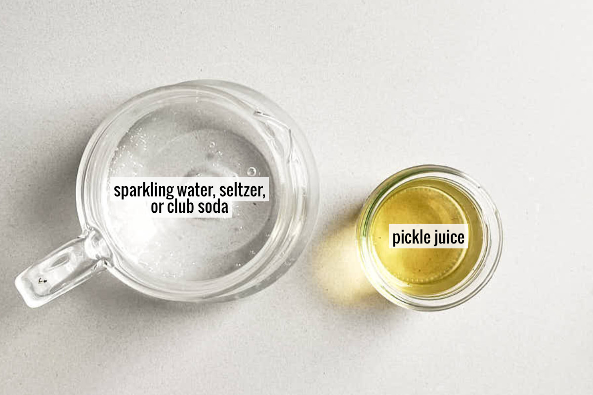 A small pitcher of bubbly water next to a small jar labeled pickle juice.