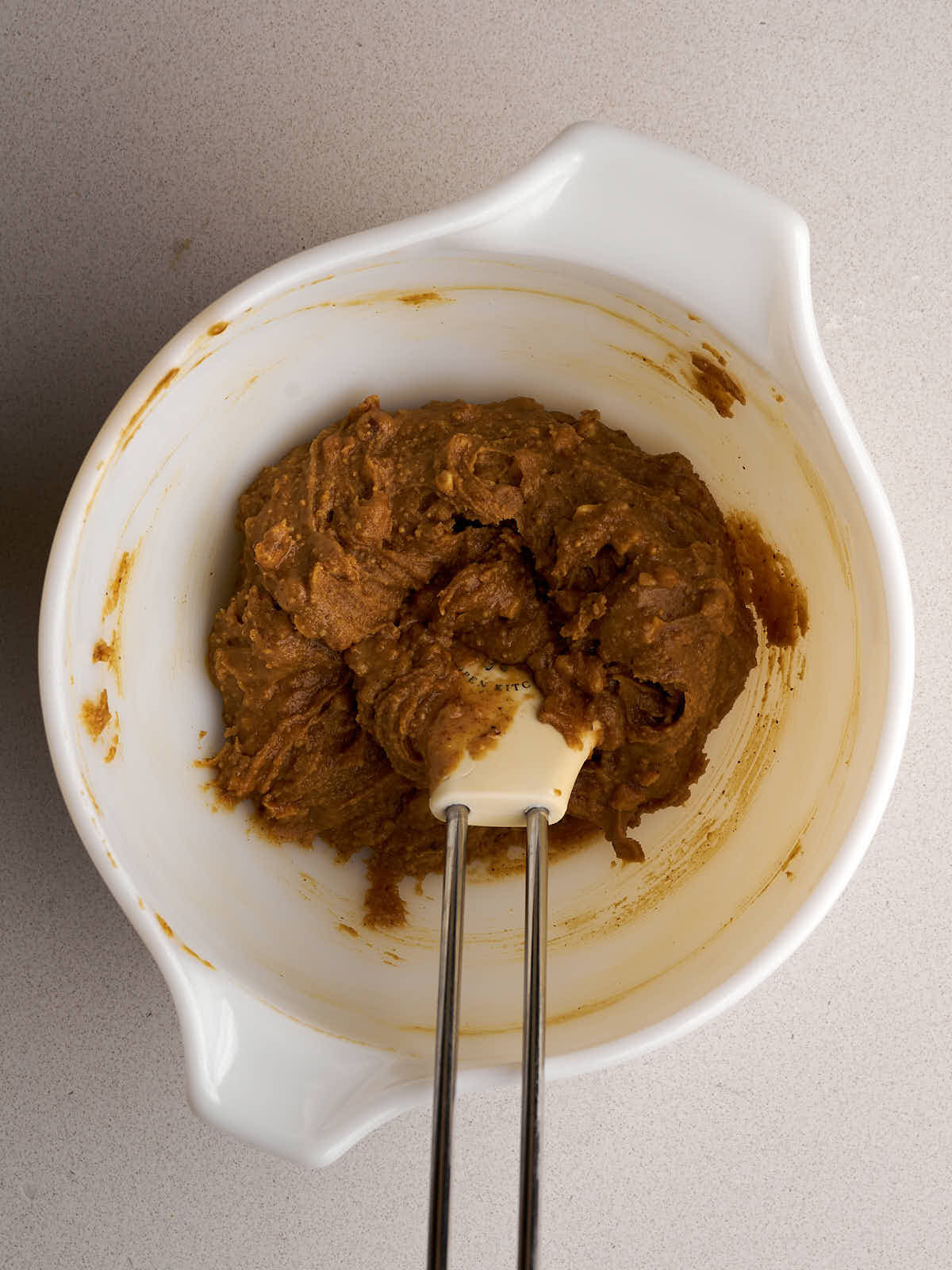 A peanut butter mixture in a white bowl with a white spatula.