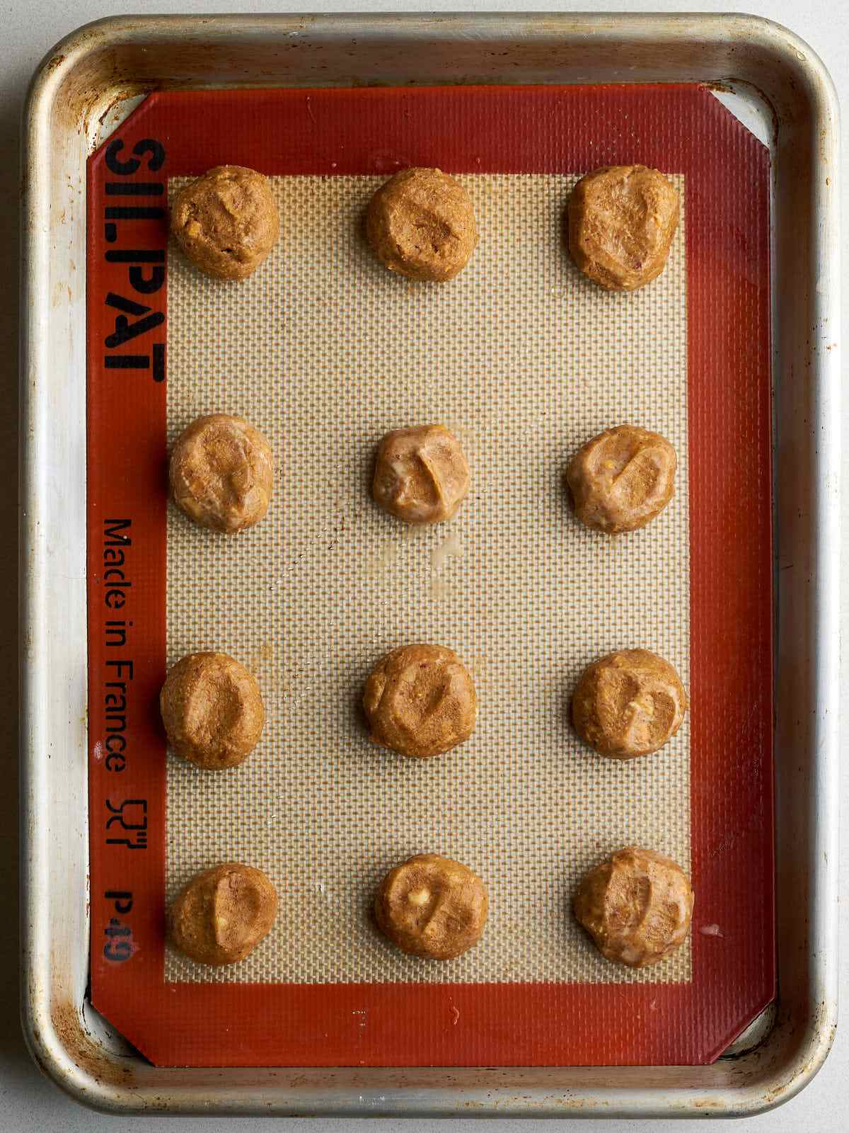 Blobs of peanut butter arranged on a baking sheet.