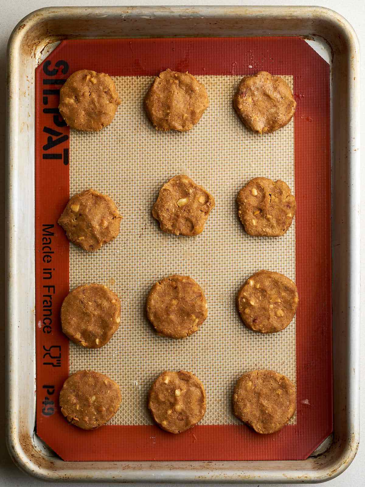 Flattened spheres of peanut butter on a baking sheet.