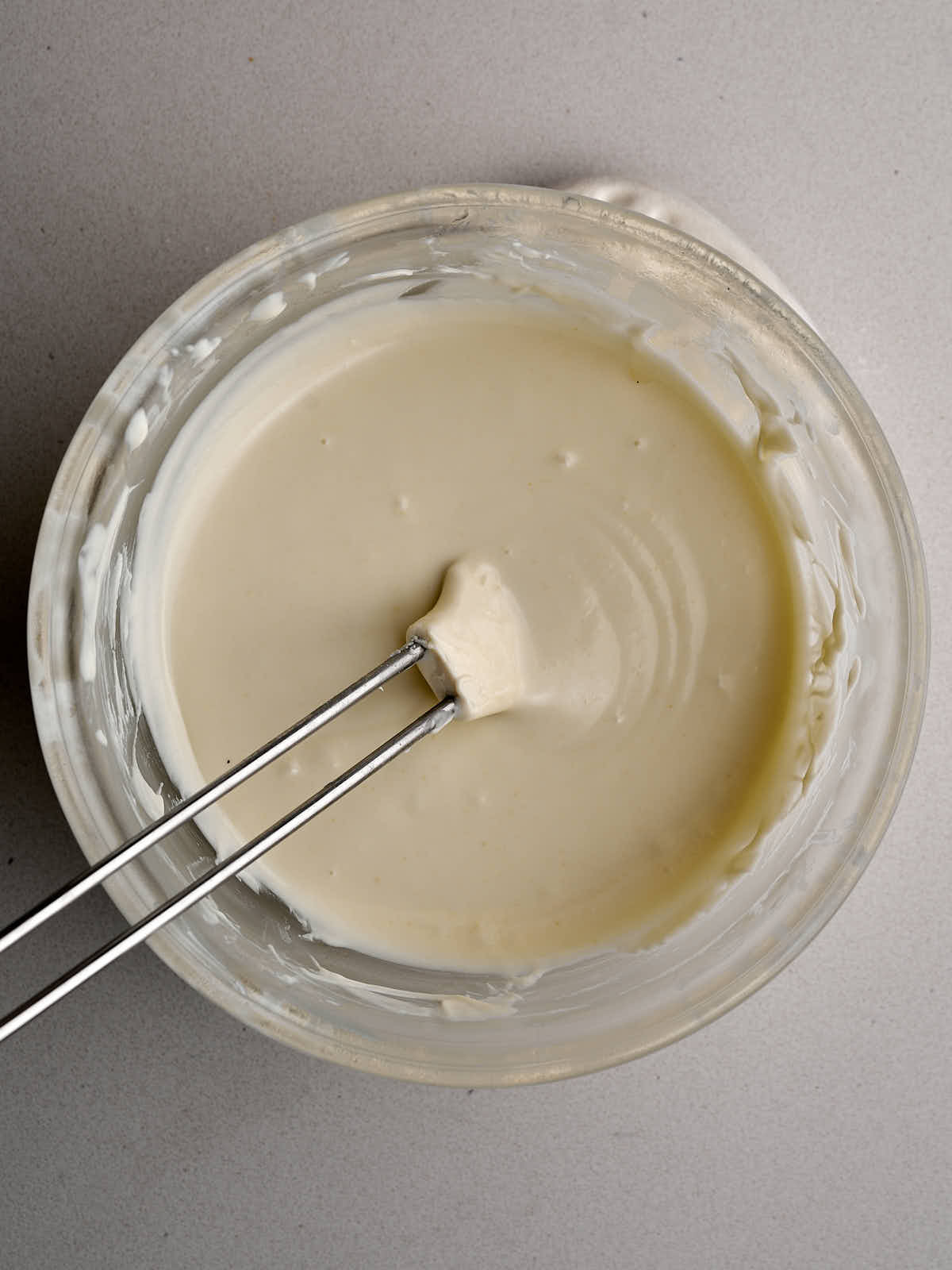 Smooth, melted white chocolate in a glass bowl.