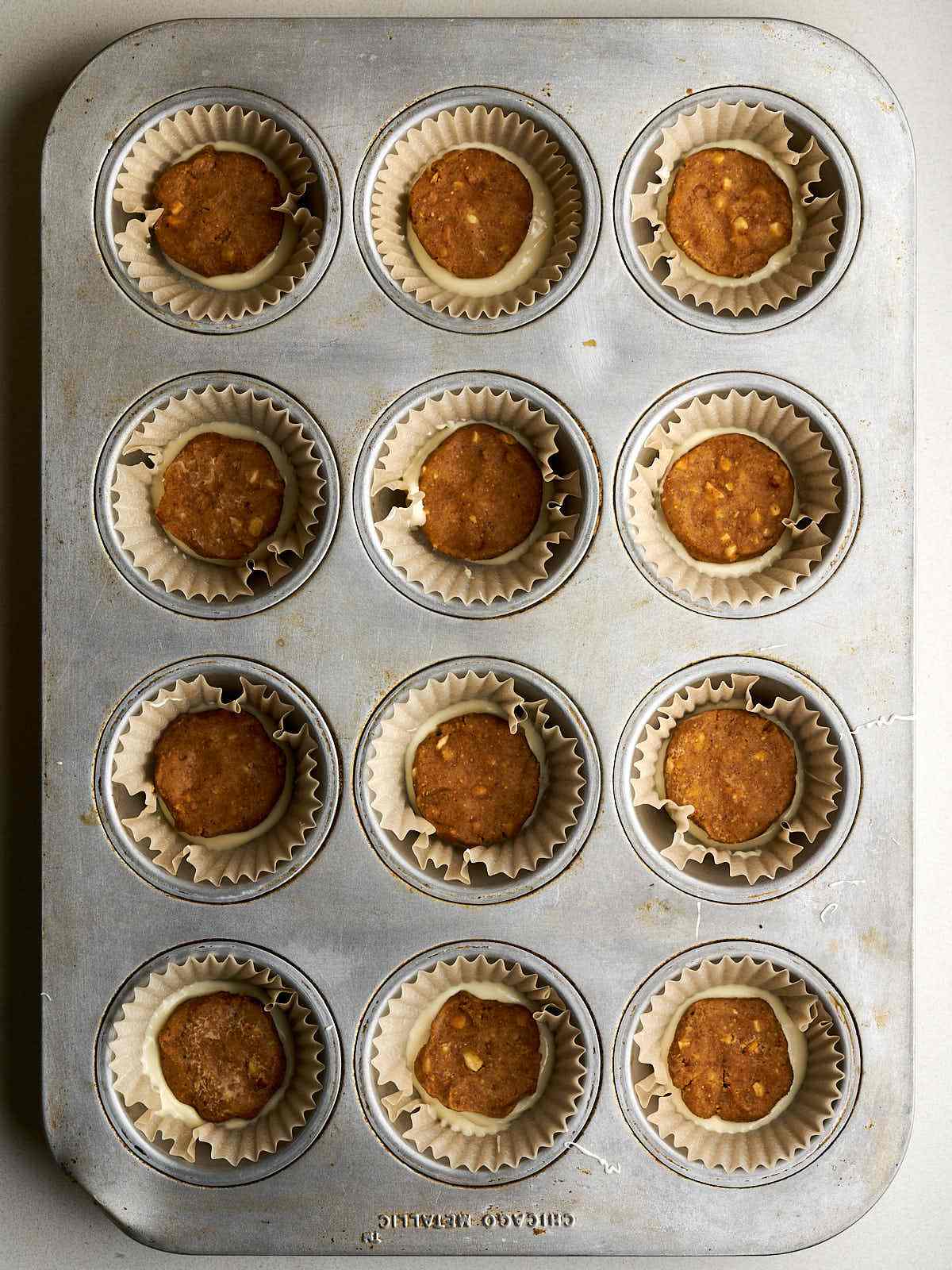 Twelve muffin liners in a pan each filled with white chocolate and peanut butter.