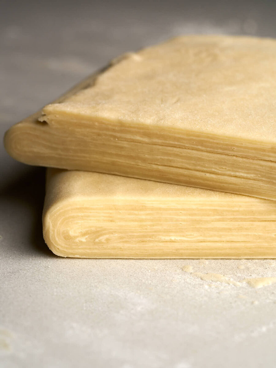 Two squares of layered puff pastry stacked on top of each other.