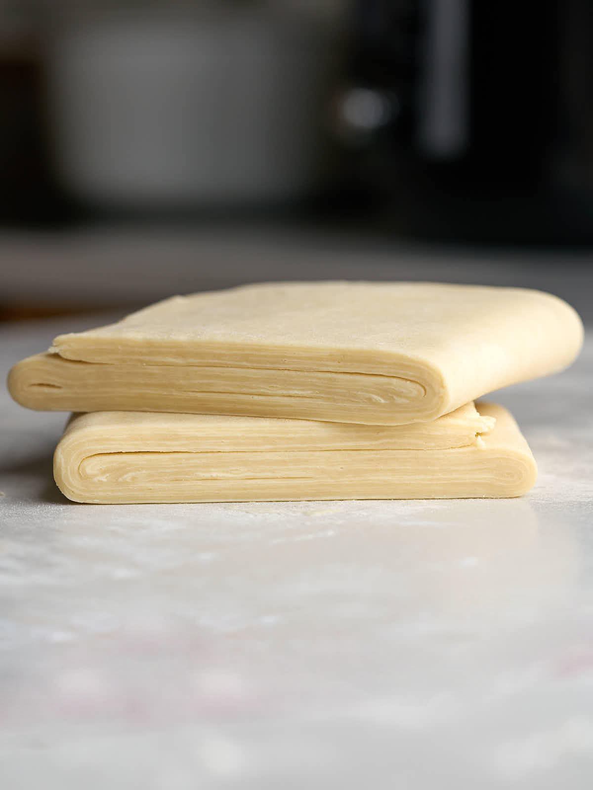 Two squares of layered puff pastry stacked on top of each other.