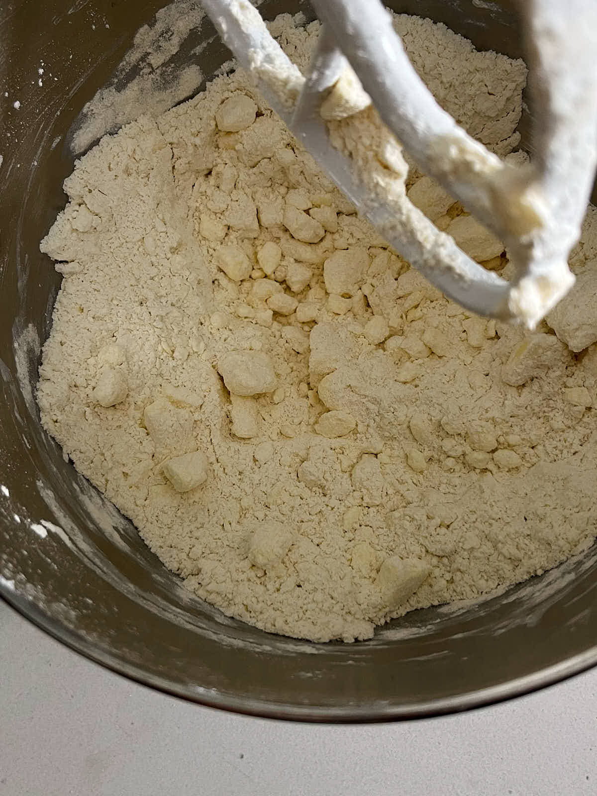 Flour and chunks of butter in the metal bowl of a stand mixer.